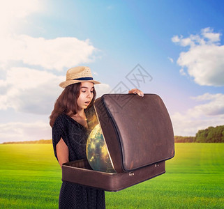 女子在草地上拿着一个半开放的手提箱图片