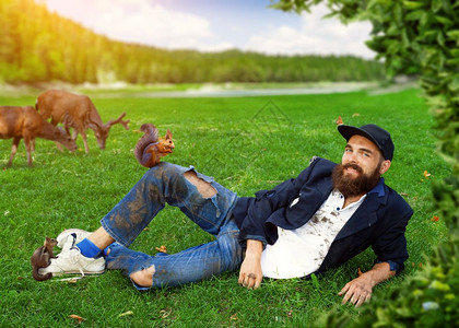 和动物一起躺在草坪上快乐的流浪汉图片