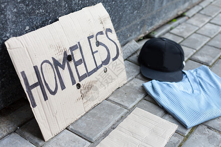 无家可归者的纸板城市墙附近的衬衫和帽子高清图片