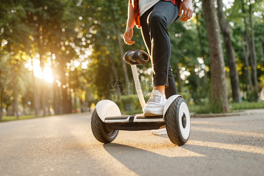 在夏季公园的旋律板上骑着男青年的子用电旋律板进行户外娱乐使用平衡技术进行生态运输图片