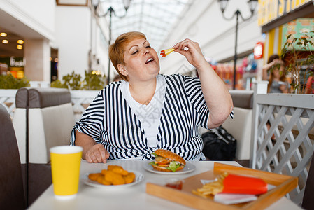 严重超重的女人在餐厅吃汉堡图片