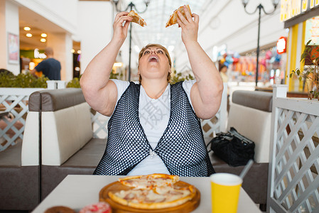 肥胖症超重的女人吃披萨背景图片