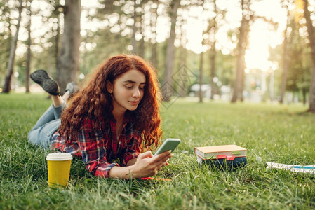 女学生在夏季公园的草地上喝咖啡图片
