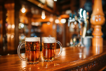 木制酒吧柜台上的两杯啤酒宏观没有人octfes符号或概念杯子上装有金饮料和泡沫在酒吧的桌子上闭路背景模糊背景图片