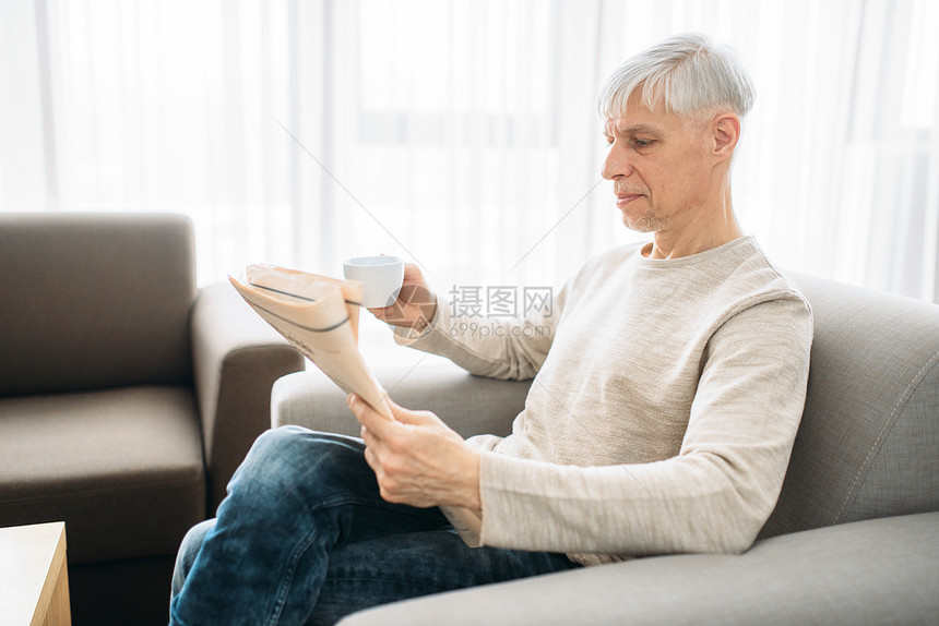 老人坐在沙发上阅读报纸图片