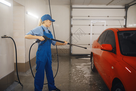 女洗衣工穿着制服用高压清洗汽车业务图片