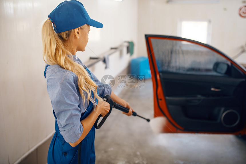 身穿制服的妇女用高压水枪清洁车辆车门图片