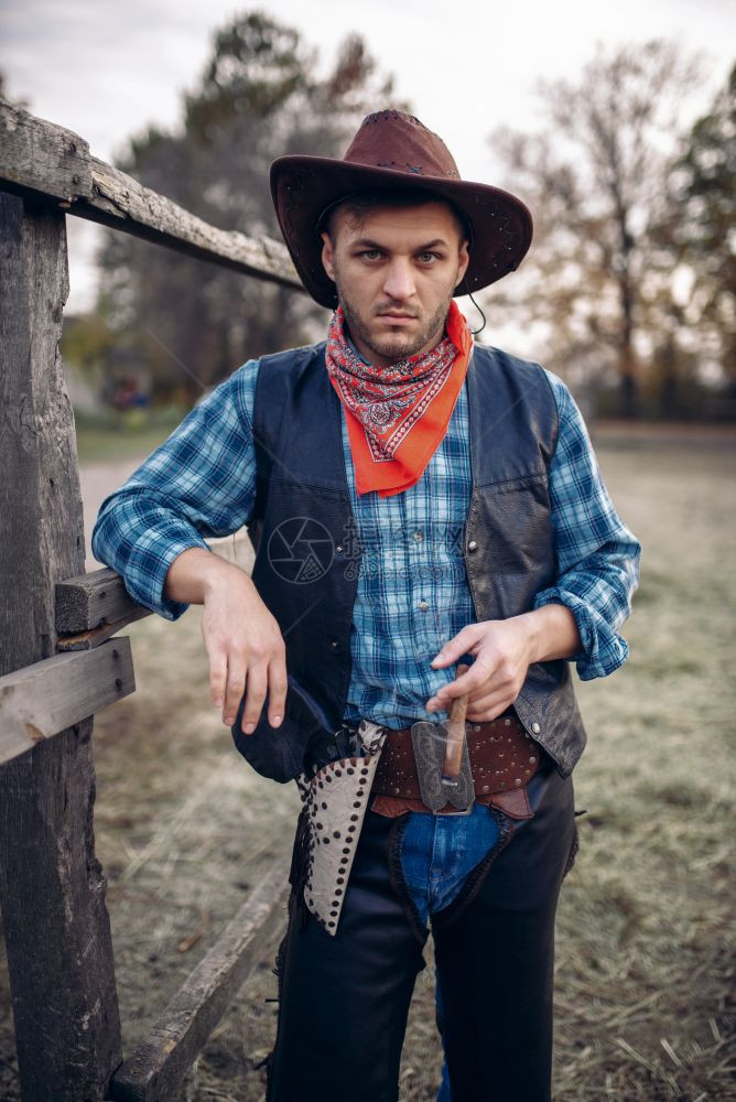 野蛮的牛仔在马圈里德克萨斯牧场里西部古老的男农场里持男子野生西部活方式雪茄在马圈里图片
