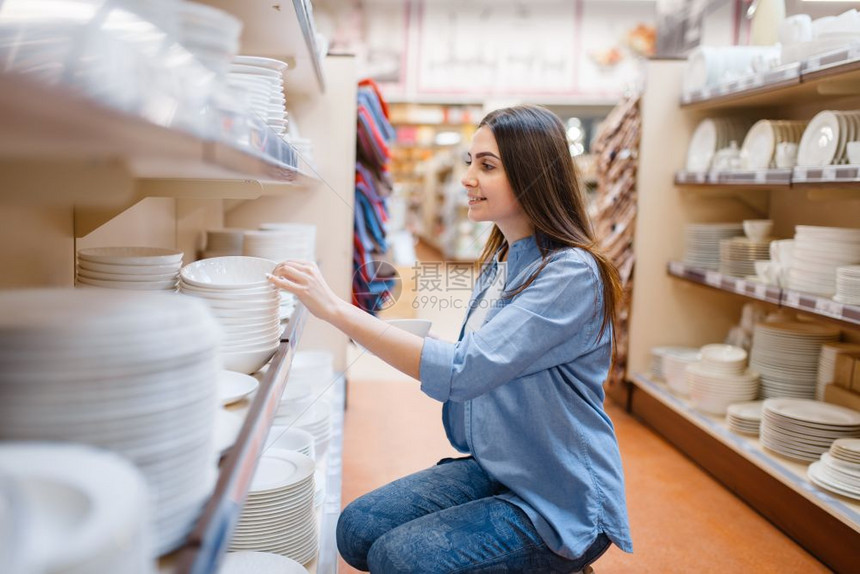在家用具商店中选择车牌的年轻女在市场上购买家用物品在厨房家具供应店的女士图片