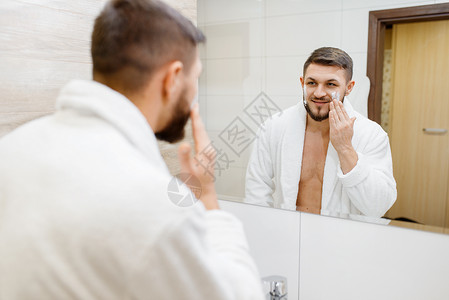 穿浴袍的男子在浴室用洗面奶洗脸图片