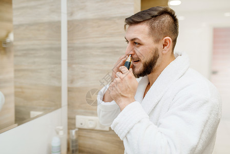 穿浴袍的男子在浴室用工具摘鼻毛图片