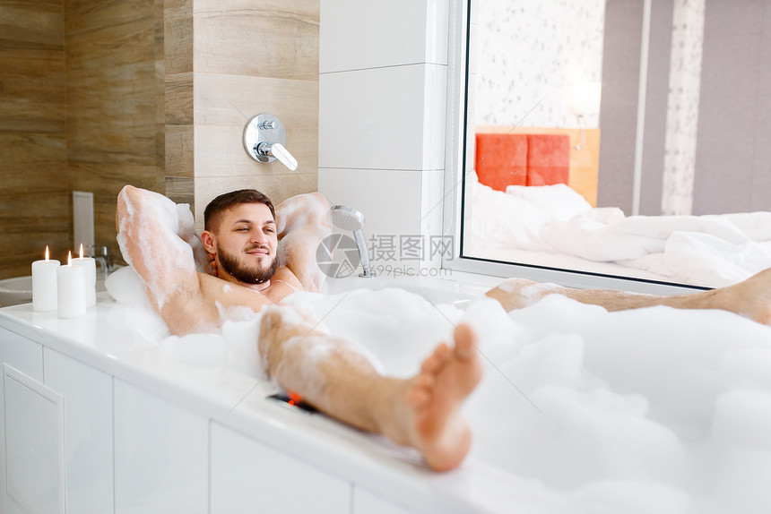 男人在浴缸用泡沫洗澡的特写镜头图片