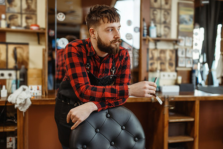 约古沙龙专业理发店是一个时髦的职业男理发师在倒古型廊剪裁附件理发师在椅子上摆起剃刀理发师在椅子上摆着剃刀背景