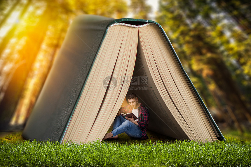 阅读概念男人坐在大书下的草地上阅读从文学中获取知识图片