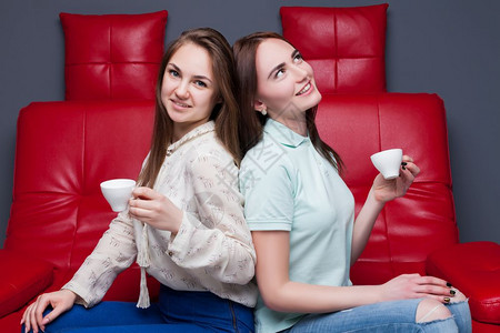 两个女孩端着咖啡坐在沙发上图片