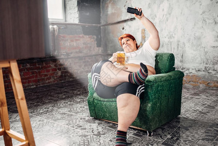 坐在椅子上和喝啤酒懒惰肥胖不健康生活方式肥胖女图片