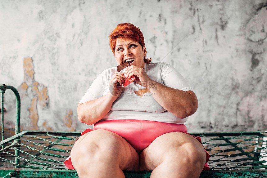 体重女人坐在床上吃巧克力图片