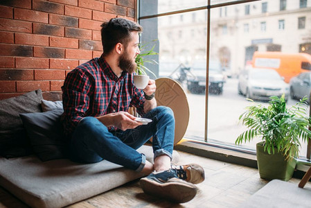 坐在沙发上喝咖啡的男人图片