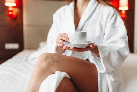 浴袍中的女用手握着一杯咖啡早安概念图片