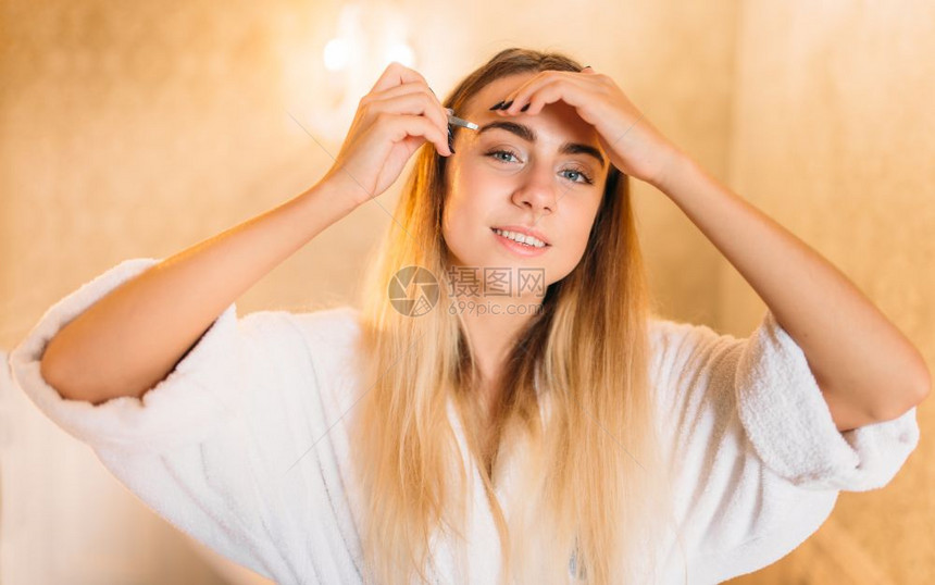 穿着白浴袍的女人在浴室做皮肤护理图片