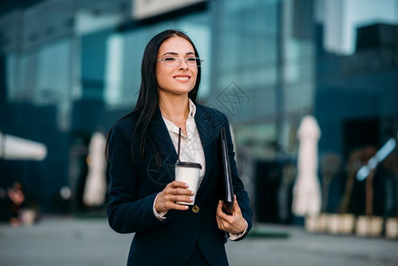 手拿笔记本和咖啡的年轻女商人图片