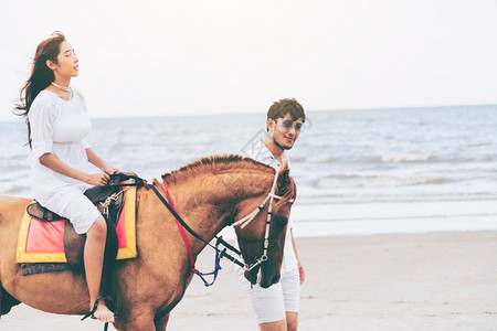 年轻夫妇在暑假海滩骑蜜月马年轻夫妇在热带海滩骑马图片