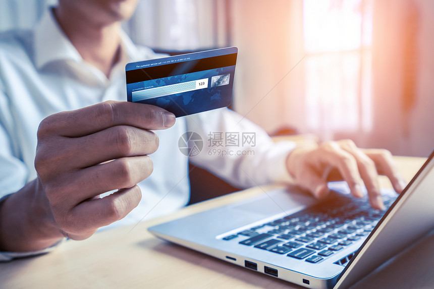 青年男子通过笔记本电脑网上购物在线付款时使用信卡图片