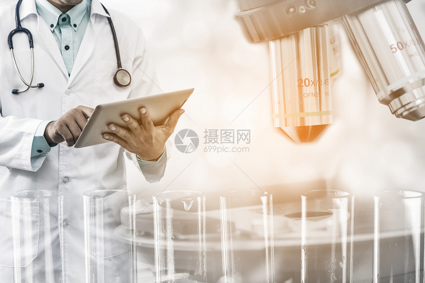 医学科研究与发展概念持有平板电脑的医生具有实验室背景的科学仪器显微镜和化学测试管图片