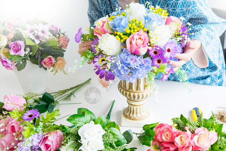 年轻女商人花卉店主在其商手工艺品和中制作或安排人工鲜花背心背景图片