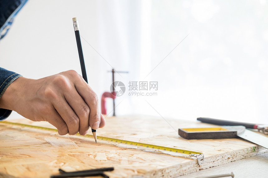 木匠仔细研究工的程计划他是在工作场所成功的创业者在与切割工一起的建筑地作上打钉子图片
