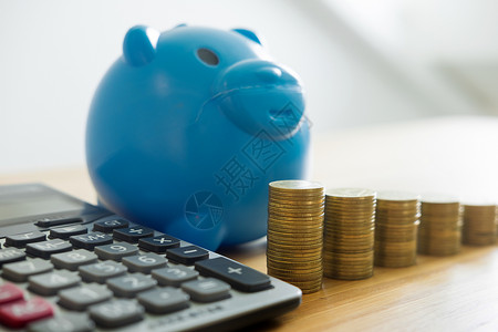小猪银行和堆叠的硬币塔上面有工作桌的图表数据投资增长金节省的概念背景图片
