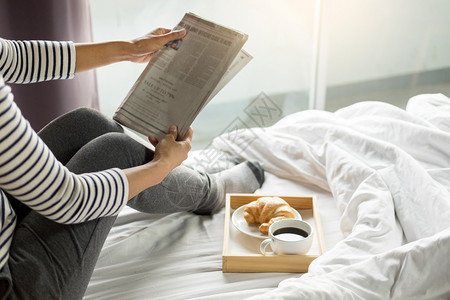 在床上看报纸吃早餐的女人图片