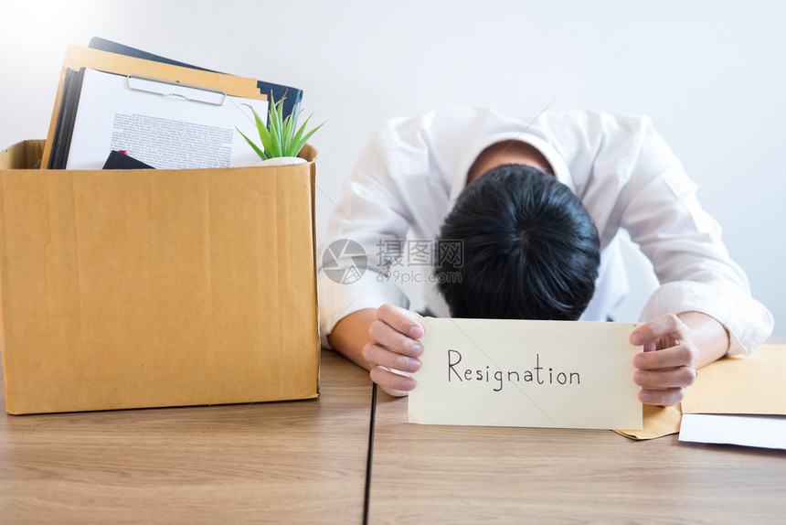 商人持有辞职文件用棕色纸箱包装个人公司改变工作失业或辞职概念图片