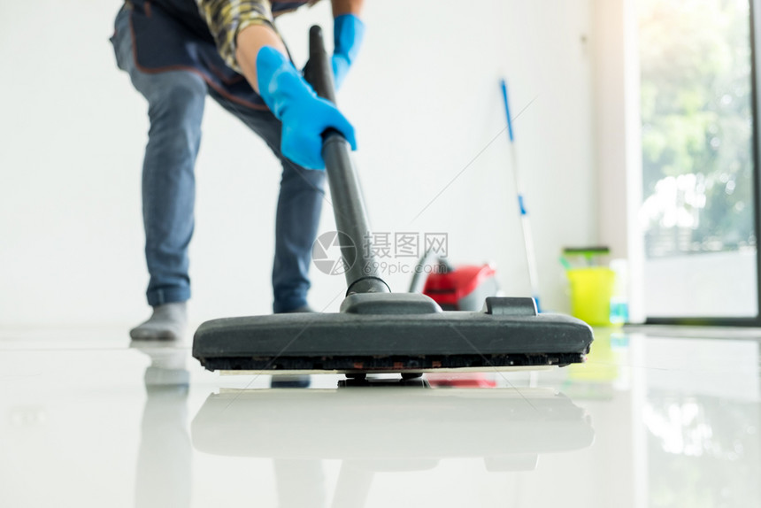 有吸引力的年轻男子正在家庭帮老婆的地板上清洗真空式商业洁设备图片