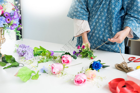 制作花束年轻女商人花卉店主在其商手工艺品和中制作或安排人工鲜花背心背景