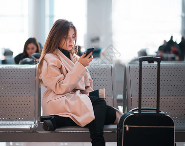 机场女商人在候空中旅行概念是临时女商人随手提箱坐着混合种族女职业图片