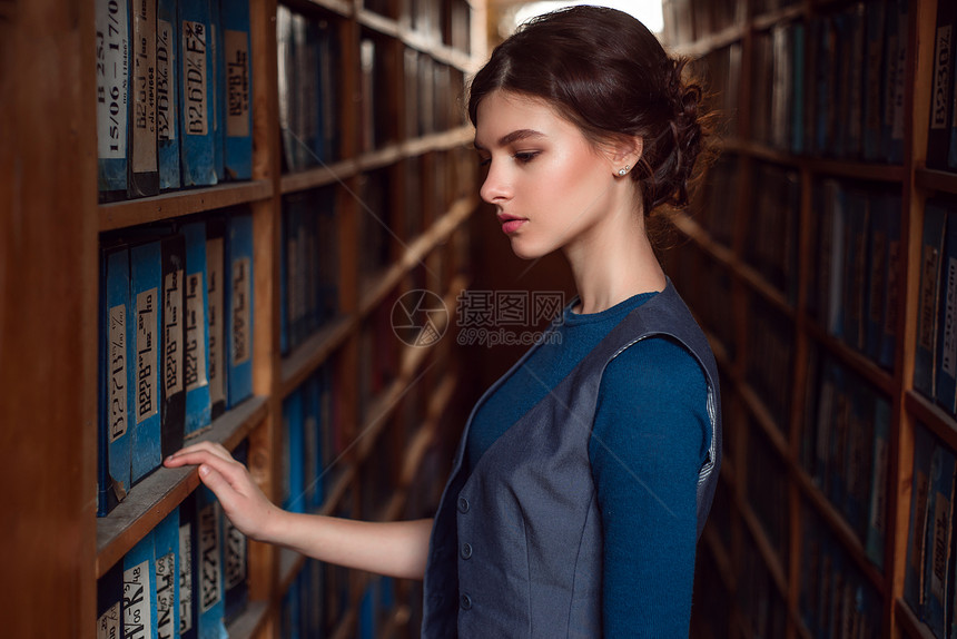 女学生在图书馆架之间挑选书籍图片