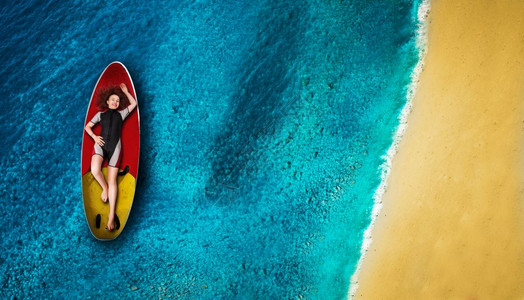 漂亮的女运动员穿湿衣服的风雪躺在船上最观的海洋和背景的海岸上图片