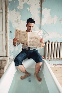 商人坐在浴缸边看报纸图片
