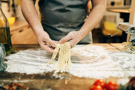 做意大利面木制厨房餐桌上做自制意粉的男厨师背景