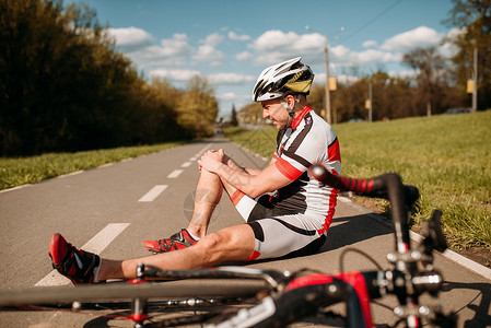 一名骑自行车的男子在自行车道上骑车时从自行车上摔下来撞到了膝盖图片