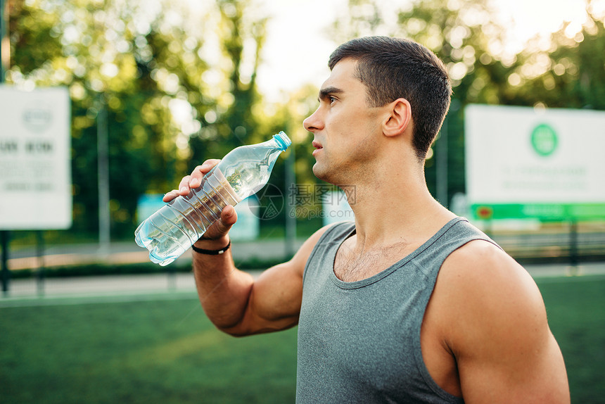 男运动员在户外健身运动时喝水图片