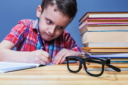 戴眼镜的书戴眼镜的小男孩在学习背景