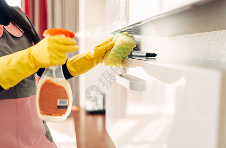 带手套的女佣用清洁喷雾洗家具背景图片