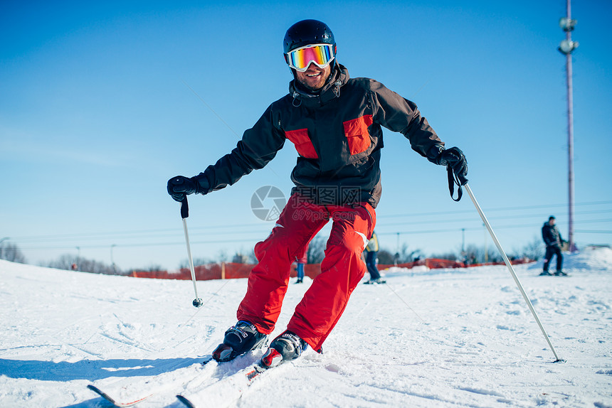 戴头盔和眼镜的滑雪车从高速斜坡下来图片