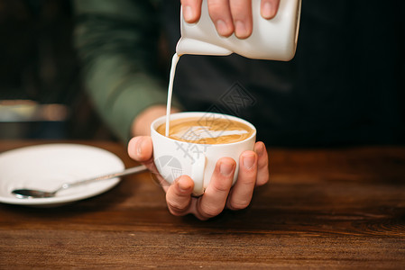 黑白的桌子盘和勺在背景上黑白的手在咖啡上加奶油图片