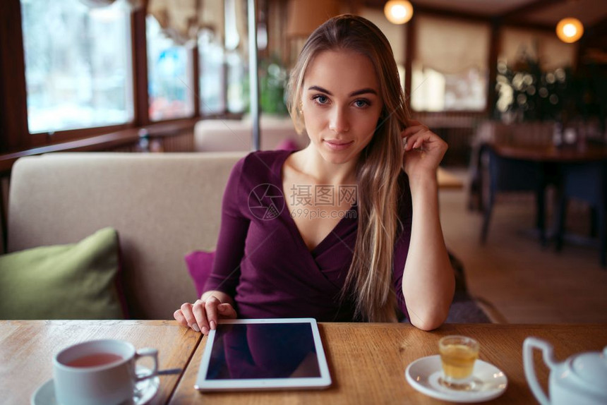 年轻女子坐在咖啡店使用平板电脑图片