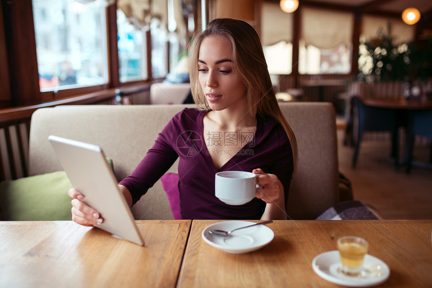 年轻女子坐在咖啡店使用平板电脑工作图片