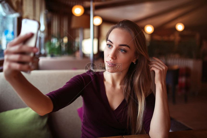 年轻美女在咖啡店做自拍图片