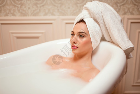 美丽的女人在充满泡泡的浴缸内沐浴图片